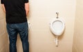 Man standing in front of a white pissoir in bathroom Royalty Free Stock Photo