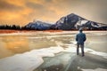 Man standing on frozen Vermilion Lakes in Banff watching golden sunrise over Mount Rundle Royalty Free Stock Photo