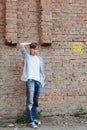 Man  standing in full size near brick wall background  and scratching rights hand your heads hair Royalty Free Stock Photo