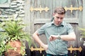 Man standing at garden looking at hand watch.