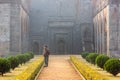 A man standing in the gardens of the misty ruins of the ancient Adina Masjid mosque in