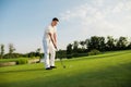 A man is standing on a golf course and getting ready to hit the ball with a golf club Royalty Free Stock Photo