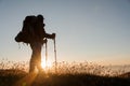 Man standing on the hill with hiking backpack and sticks looking at the sunset Royalty Free Stock Photo