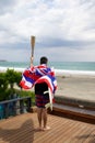 Man hold a torch used in large sporting event , with Hawaiian flag and surfboard.