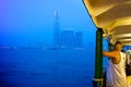 A man standing on the HongKong ferry during blue hour.