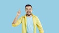 Man standing isolated on a blue background has an idea, smiles and points his finger up Royalty Free Stock Photo