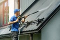 Man standing on ladder and cleaning house metal roof with high pressure washer Royalty Free Stock Photo