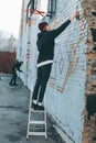 man standing on ladder and painting colorful graffiti