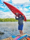 Man standing on lake river wooden dock and holding kayak boat on his head Royalty Free Stock Photo