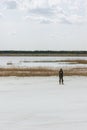 Man Standing By The Lake Among White Quartz Sand