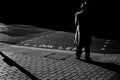 Man standing in a lonely street at night, shadows falling on street