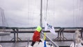 Man standing in a motor boat moored near the bridge with people crossing it on grey cloudy sky background. Art. Group of Royalty Free Stock Photo