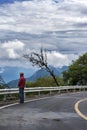 A man standing by the mountain road