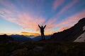 Man standing on mountain top outstretching arms, sunrise light colorful sky scenis landscape, conquering success leader concept. Royalty Free Stock Photo