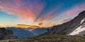 Man standing on mountain top raising arms, sunrise light colorful sky scenis landscape, conquering success leader concept.