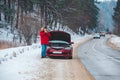 man standing near broken car with opened hood calling help