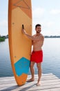 Man standing near SUP board on pier Royalty Free Stock Photo