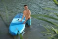 Man standing near SUP board in river water on sunny day Royalty Free Stock Photo