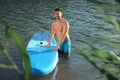 Man standing near SUP board in river water on sunny day Royalty Free Stock Photo