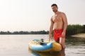 Man standing near SUP board in water, space for text Royalty Free Stock Photo