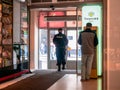 A man standing near the yellow terminal with the Tinkoff Bank logo. Armed policemen exits shopping center. Men in police uniform Royalty Free Stock Photo