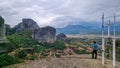 Meteora - Man standing next to cross with bell on top of rock Aghio Pnevma Holy Spirit. Royalty Free Stock Photo