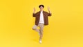 Man standing on one leg making om gesture, yellow background Royalty Free Stock Photo