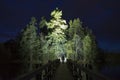 Man standing outdoor at dark night shining with flashlight Royalty Free Stock Photo