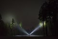 Man standing outdoor at night in forest shining with two flashlights up in dark sky and at trees Royalty Free Stock Photo