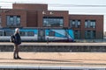 Man standing on a platform looking at a Transpennine Express train