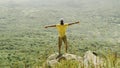 Man standing with raised arms on peak of rock in summer Royalty Free Stock Photo