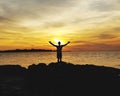 Man standing at seashore against sunset sky