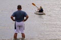 Man looking after his wife who is paddling away with kayak Royalty Free Stock Photo