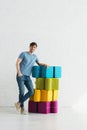 Man standing and smiling near colorful poufs near brick wall