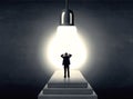Man standing on a step in front of a huge light bulb Royalty Free Stock Photo