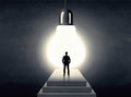 Man standing on a step in front of a huge light bulb Royalty Free Stock Photo