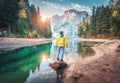Man is standing on the stone on Braies lake at sunrise in autumn