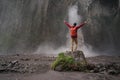 Man standing on stone and looking on waterfall