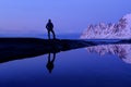 Man standing at Tungeneset, his mirror reflection in the water, mountains in the background, Senja, Troms, Norway Royalty Free Stock Photo