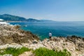 Man standing on stony cliff by azure Meidterranean Sea in Roquebrune Cap Martin in France Royalty Free Stock Photo