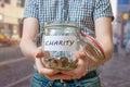 Man standing on street is collecting money for charity and holds jar