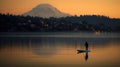 Man standing on top of paddleboard in middle of lake, surrounded by mountains. He is positioned near center of frame Royalty Free Stock Photo