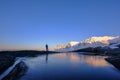 Man standing at Tungeneset, his mirror reflection in the water, mountains in the background, Senja, Troms, Norway Royalty Free Stock Photo