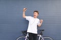 Man standing by a white bicycle, listening to music in headphones with a smartphone in his hands and dancing Royalty Free Stock Photo