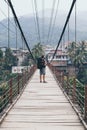 Man standing on wooden suspension bridge in a mountain village of Laos Royalty Free Stock Photo