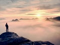 Man stands alone on the peak of rock. Hiker watching to autumn Sun at horizon Royalty Free Stock Photo