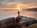 Man stands alone on the peak of rock. Hiker watching to autumn Sun at horizon