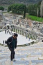 Man stands atop a set of weathered stone steps leading down to Ephesus Ancient Greek Theatre