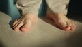 A man stands barefoot on a light floor, close-up, camera moving