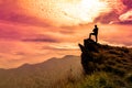 The man stands on a cliff top and orange sky